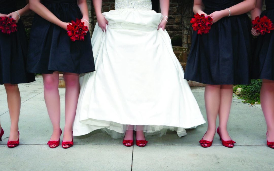 Bridesmaids and bride wearing red shoes and holding red bouquets.