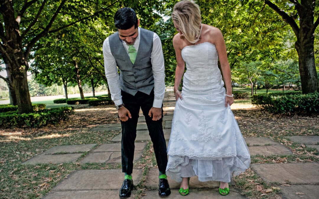 Couple in wedding attire walking on a park pathway with trees.