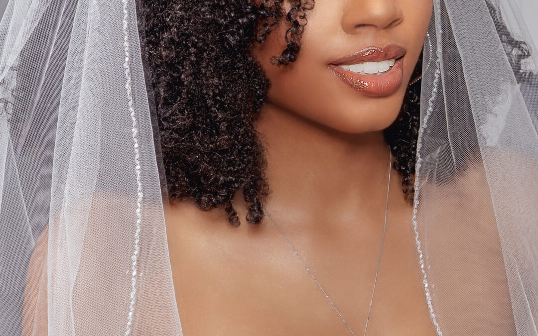 Elegant bride with curly hair wearing a wedding veil and dress.