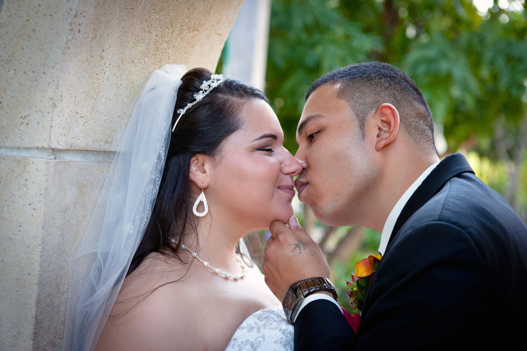 Bride and groom sharing a romantic kiss outdoors on wedding day.